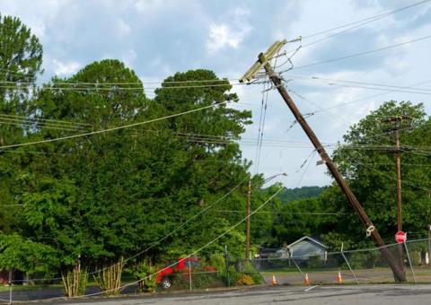 damaged utility pole tilting with wires drooping to ground
